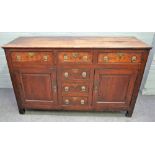 An 18th century oak dresser base with three frieze drawers, over three dummy, flanked by cupboards,