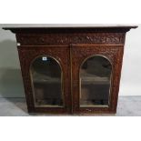 An early 20th century rosewood display cabinet with arch panelled glass doors and carved decoration,