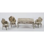 A group of miniature silver furniture, comprising; a shaped rectangular table,