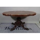 A Victorian figured walnut centre table, the shaped top on turned column and four scroll supports,