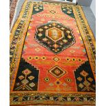 A North West Persian rug, the madder field with a bold angular black medallion and black spandrels,