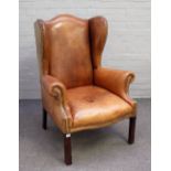 A George II style studded brown leather upholstered wingback on channelled square supports,