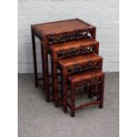 A nest of four Chinese hardwood occasional tables, with parcel gilt and floral carved frieze,