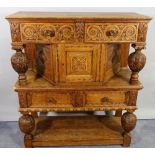 A 17th century style oak side cupboard with carved decoration on baluster turned supports,