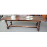 A 17th century style oak refectory table, the plank top on turned supports, 77cm wide x 258cm long.