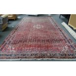 A Fereghan carpet, Persian, the madder field with an allover herate design, three border,