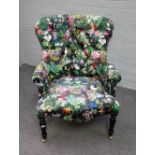 A Victorian style button back armchair, with floral pattern upholstery, on turned ebonised supports,
