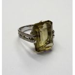 A white gold ring claw set with a cut cornered rectangular step cut smoky quartz between colourless