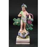 A Staffordshire pearlware figure of a putto, circa 1790, modelled standing on a rocky mound,