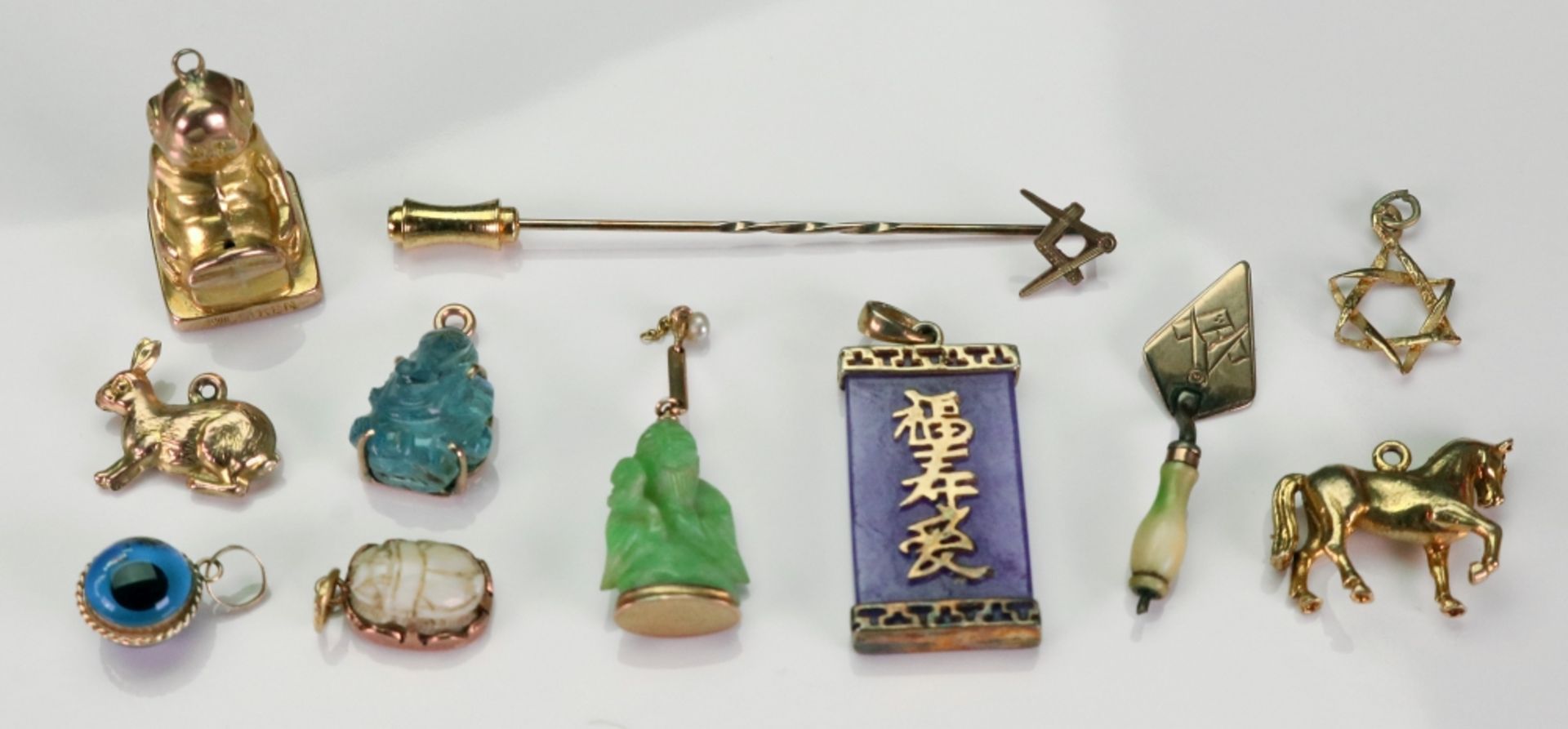 A collection of gold and yellow precious metal, hardstone-set charms,