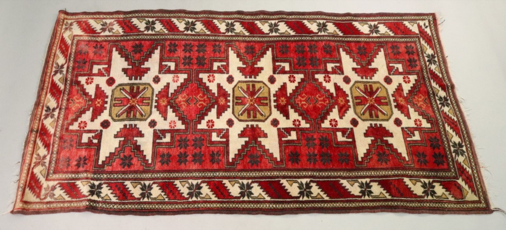 A Caucasian rug, with a Lesghi star design, on a cream and red ground,