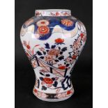 A Japanese Imari baluster vase, Meiji period, painted with flowering shrubs in a fenced garden,