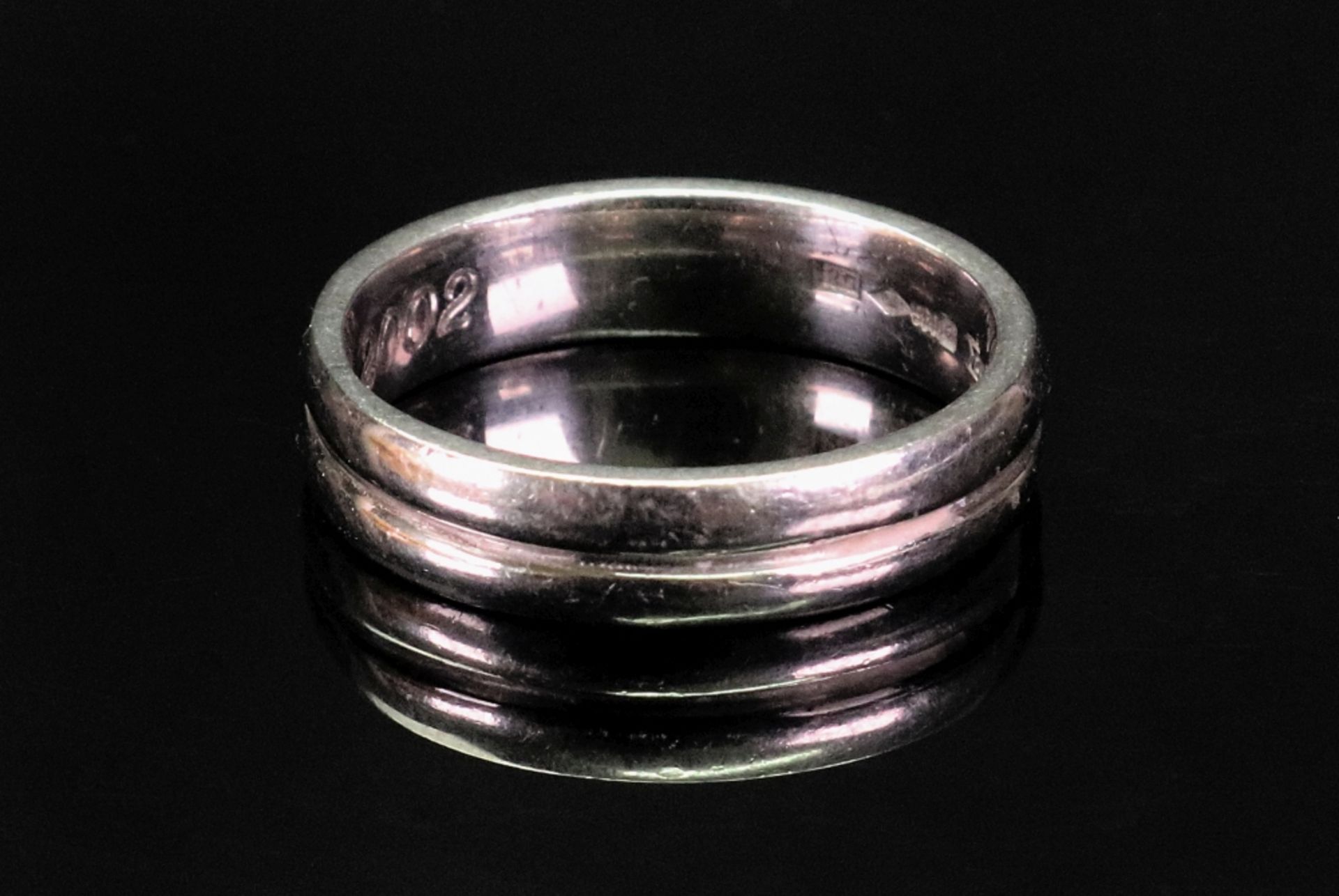 A platinum wedding ring, Millennium marks 2000, maker's mark RG, ring size T 1/2, 11.6g, inscribed.