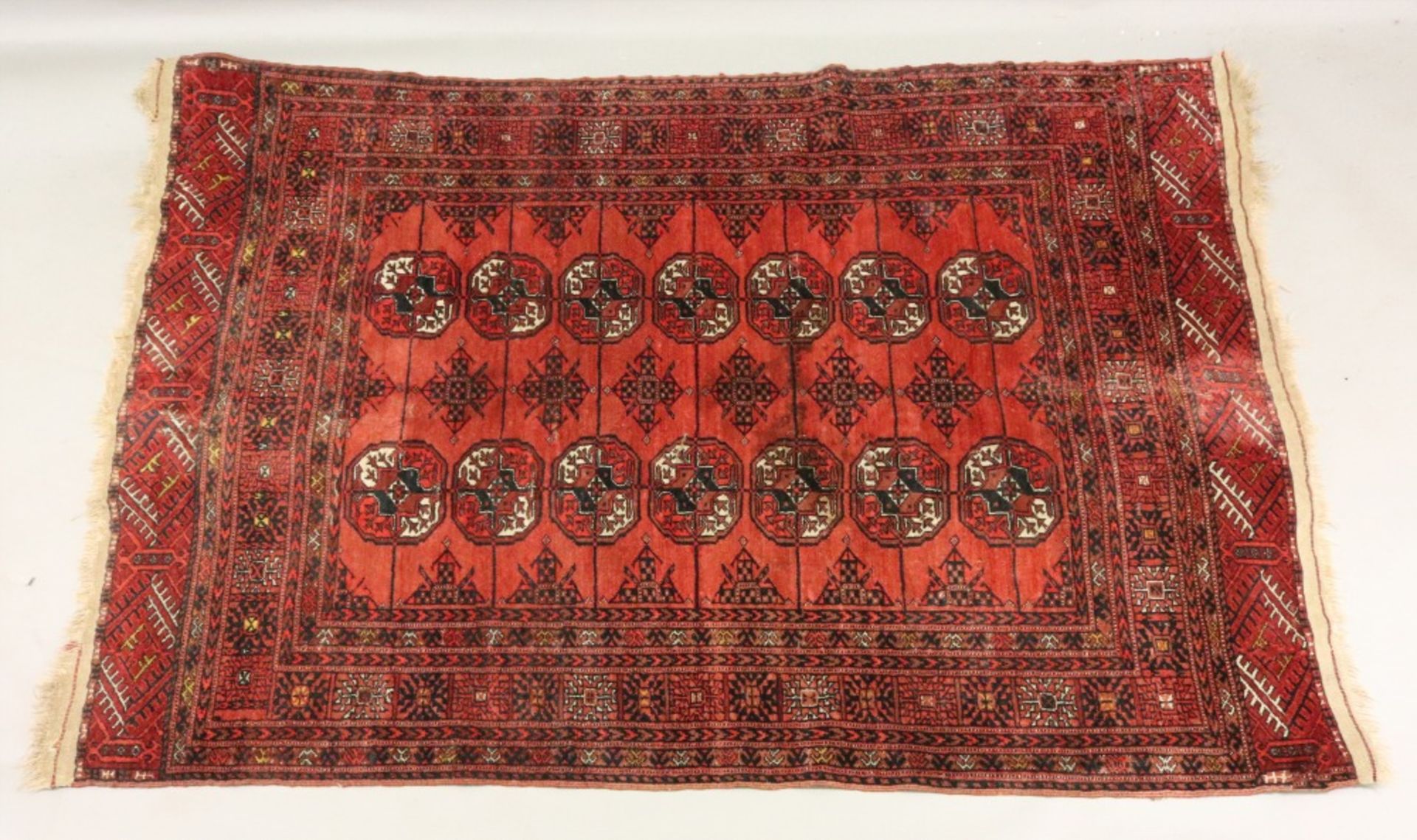 An Afgan Bokhara rug, with two rows of quartered guls on a rust ground, 176 x 125cm,