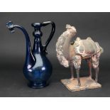 A Chinese Han type pottery figure of a Bactrian camel, modelled standing wearing a saddlecloth,