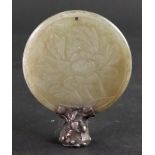 A Chinese circular jade disc, carved on one side with a flower and leaves,