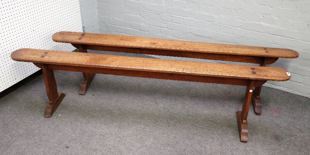 A pair of 19th century French fruitwood benches on silhouette trestle supports,