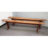 A pair of 19th century French fruitwood benches on silhouette trestle supports,