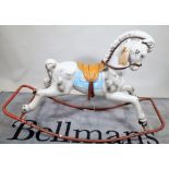 A 20th century fibre glass rocking horse on metal base, 125cm wide x 86cm high.