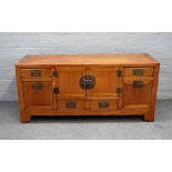 A 19th century Chinese elm low cabinet, with five cupboards over four drawers, on bracket feet,