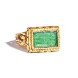 A gold ring, mounted with a close backed rectangular cut emerald,