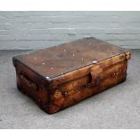 A coffee table with rectangular loose glass top on a brass studded polished leather suitcase,