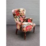 A Victorian style button back armchair with floral upholstery on turned supports,