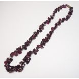A single row necklace of tumbled garnet beads, of irregular form, on a base metal clasp.