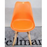 A modern orange plastic and pine dining chair.