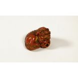 A Japanese red lacquered wood netsuke of a shishi, 19th/early 20th century,