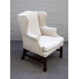 A George II style wingback armchair in cream upholstery, on block supports, 80cm wide x 103cm high.