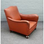 An early 20th century brown leatherette upholstered easy armchair on turned beech supports,
