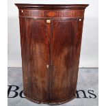 A late George III inlaid mahogany bowfront hanging corner cupboard, 76cm wide x 116cm high.