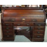 An early 20th century mahogany roll top desk with fitted interior and nine drawers about the knee,