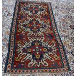 A Chelaberd Kazak Caucasian carpet, the madder field with three bold ivory medallions,