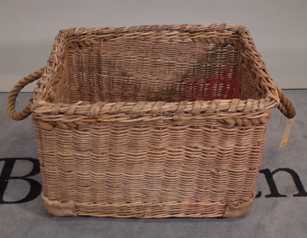 An early 20th century wicker basket with rope handles, 66cm wide x 44cm high.