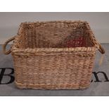 An early 20th century wicker basket with rope handles, 66cm wide x 44cm high.