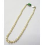 A single row necklace of graduated cultured pearls, on a white gold, jade and diamond set clasp,