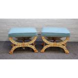 A pair of Empire style stools each with overstuffed rectangular tops on parcel gilt blue painted