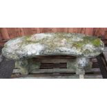 A 20th century reconstituted stone concave garden bench with carved lion mask supports,