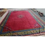 A Chinese carpet, the plain madder field with a central floral medallion,
