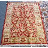 A Turkish rug, the madder field with lily-head and floral vine design, cream palmette border,