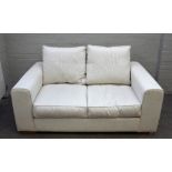 Heals; a Moretta small seat sofa upholstered in cream fabric on block feet, 163cm wide x 75cm high.