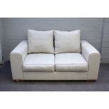 Heals; a Moretta small seat sofa upholstered in cream fabric on block feet, 163cm wide x 75cm high.