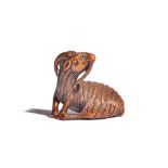 A Japanese wood netsuke of a recumbent goat, 19th century, carved with head turned across its back,