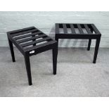 A pair of ebonised luggage stands with slatted rectangular tops on tapering square supports,