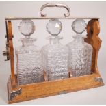 An early 20th century oak and silver plated mounted three division tantalus,