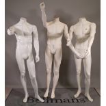 A group of three modern white adult male shop mannequins.