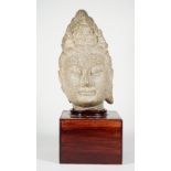A Chinese stone head of Buddha, possibly Ming dynasty, carved wearing a serene expression,