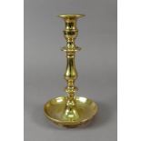 A heavy cast brass candlestick, in 18th century style, with baluster stem and dished circular base,
